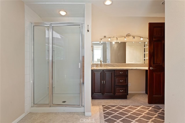 bathroom with tile patterned floors, a shower stall, vanity, and baseboards