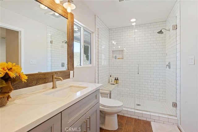 bathroom with vanity, toilet, wood finished floors, and a stall shower