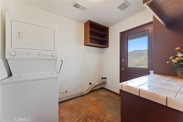 laundry area featuring laundry area, stacked washer / dryer, baseboards, and visible vents