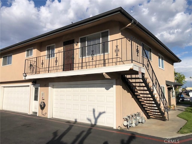 view of property featuring stairway, an attached garage, and stucco siding