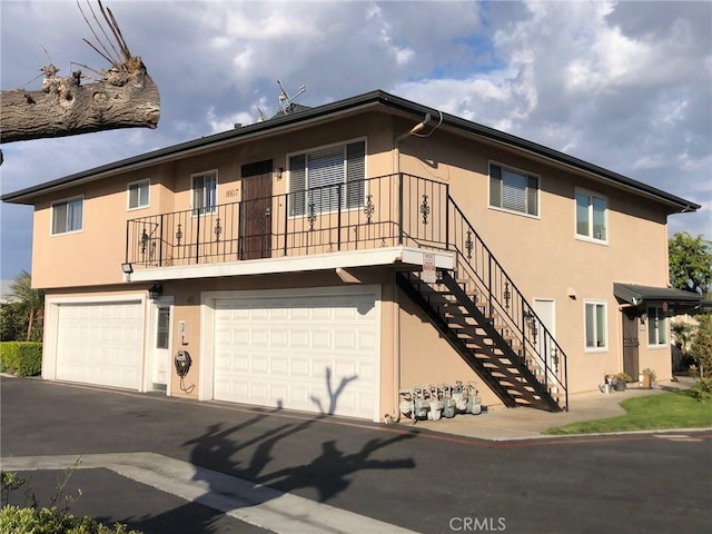 view of front facade featuring stairs, an attached garage, and stucco siding