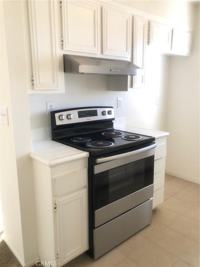 kitchen featuring under cabinet range hood, light countertops, electric range, and white cabinetry