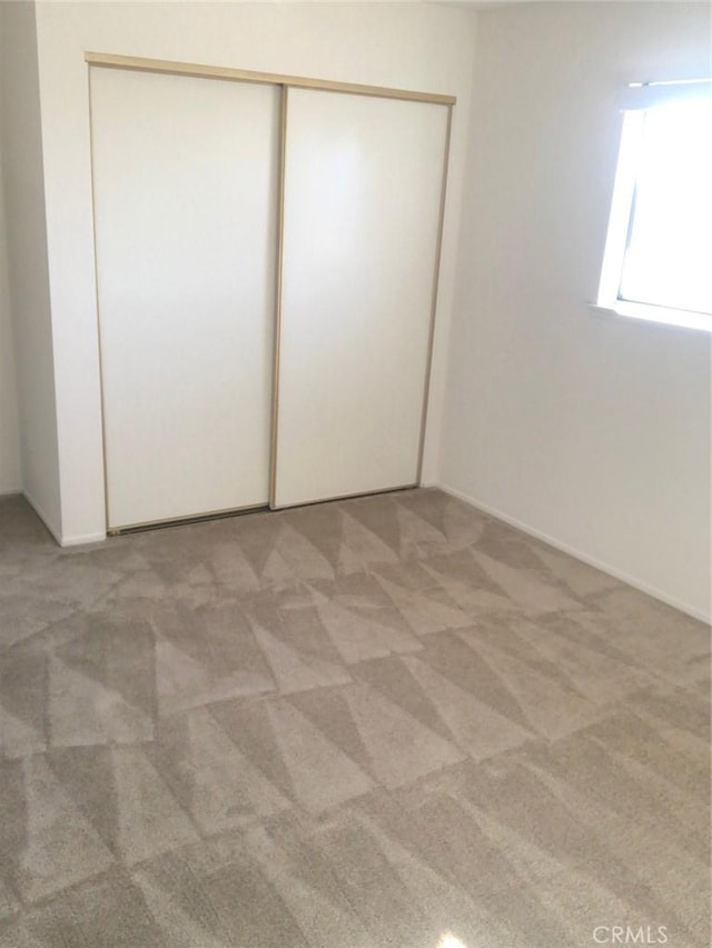 unfurnished bedroom with a closet and light colored carpet