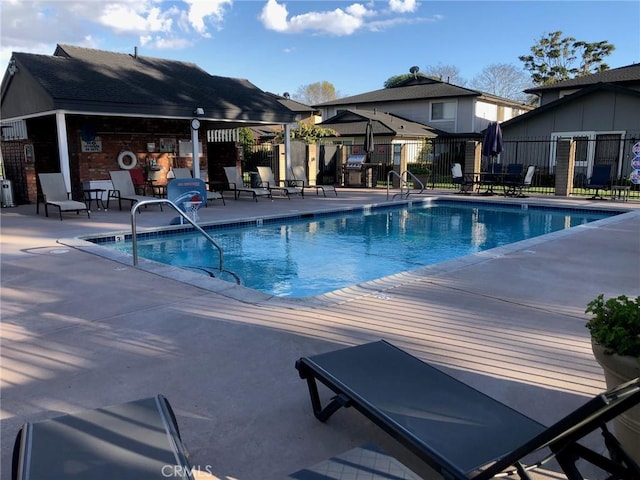 community pool with a patio and fence