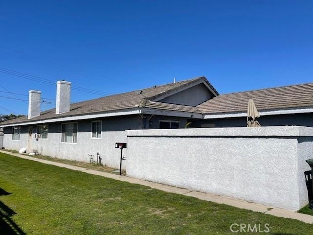 view of property exterior with a lawn and stucco siding