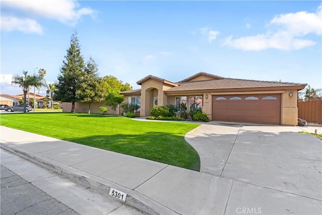 view of front facade featuring stucco siding, fence, a garage, driveway, and a front lawn