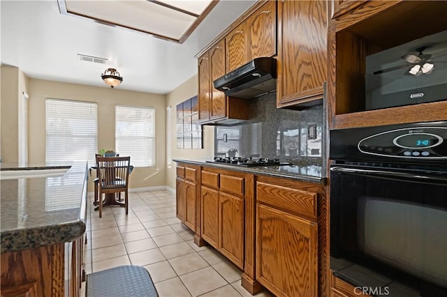 kitchen with light tile patterned floors, tasteful backsplash, visible vents, under cabinet range hood, and black appliances