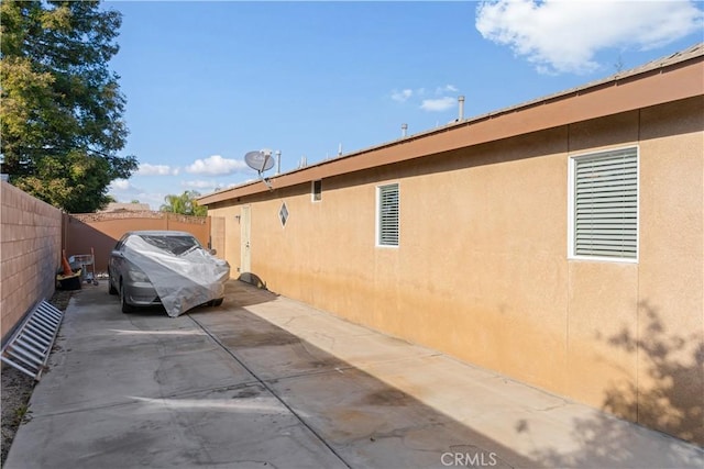 view of side of home with fence, a patio, and stucco siding