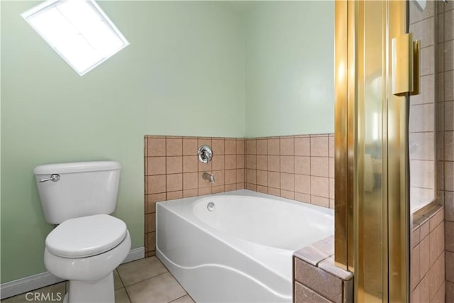 full bath featuring tile patterned flooring, baseboards, a garden tub, and toilet