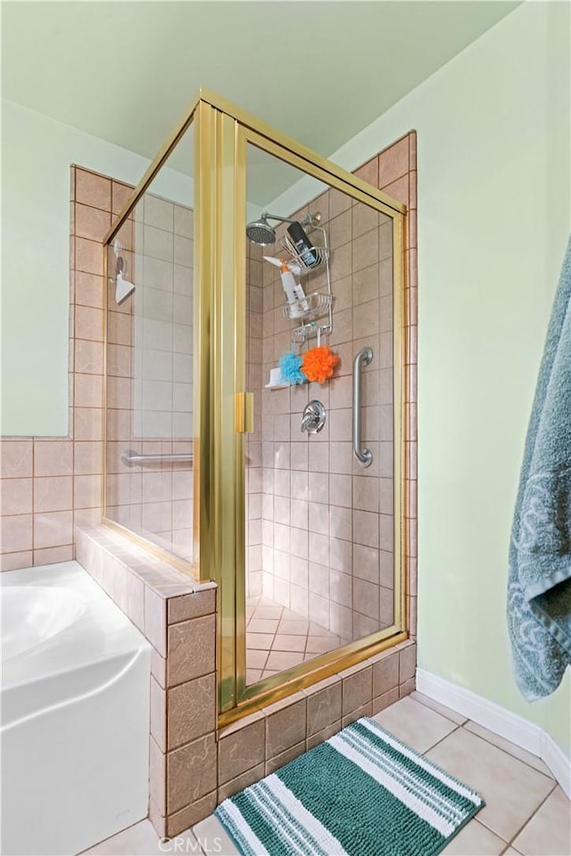 bathroom with baseboards, a shower stall, a bath, and tile patterned floors