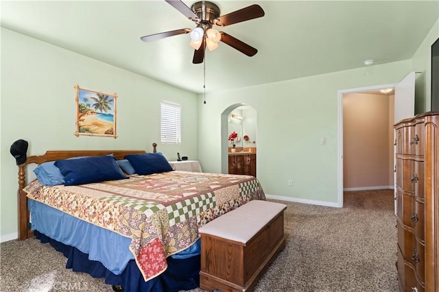 carpeted bedroom featuring arched walkways, ensuite bath, a ceiling fan, and baseboards