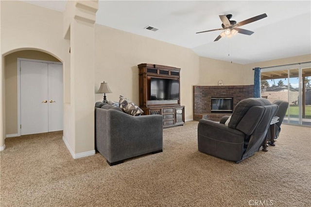 carpeted living area featuring visible vents, a ceiling fan, a brick fireplace, vaulted ceiling, and baseboards