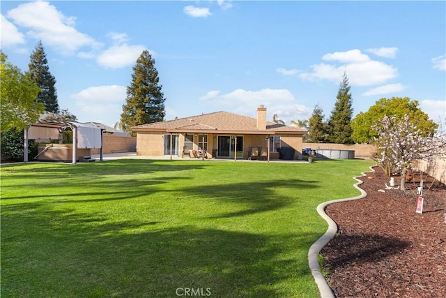 back of house with a patio area, a fenced backyard, a lawn, and a chimney