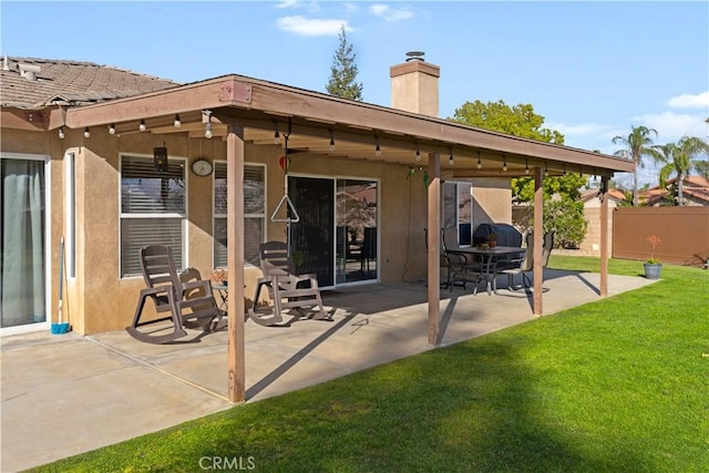 back of house with a patio area, fence, stucco siding, and a yard