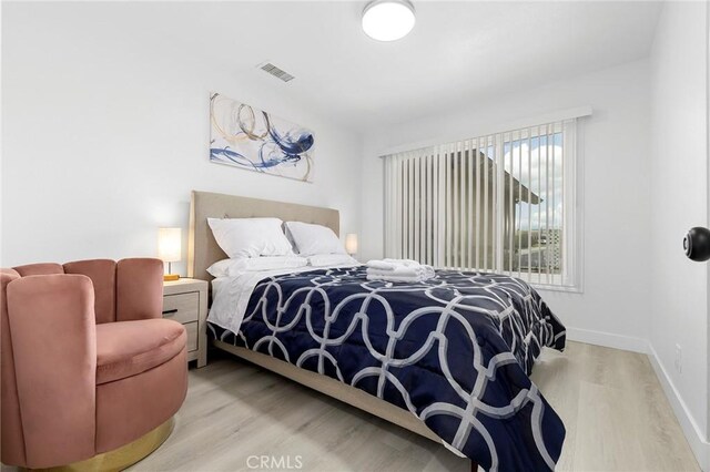 bedroom featuring visible vents, baseboards, and wood finished floors