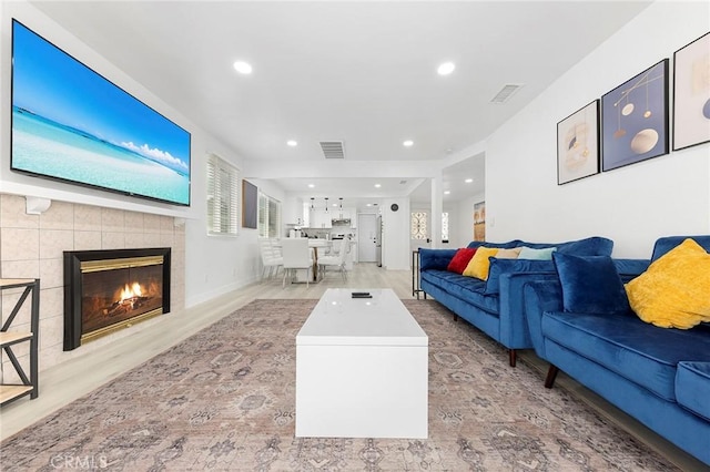 living area with recessed lighting, visible vents, a fireplace, and wood finished floors