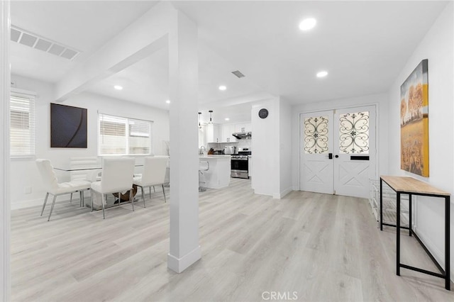 foyer entrance featuring light wood finished floors, baseboards, visible vents, and recessed lighting