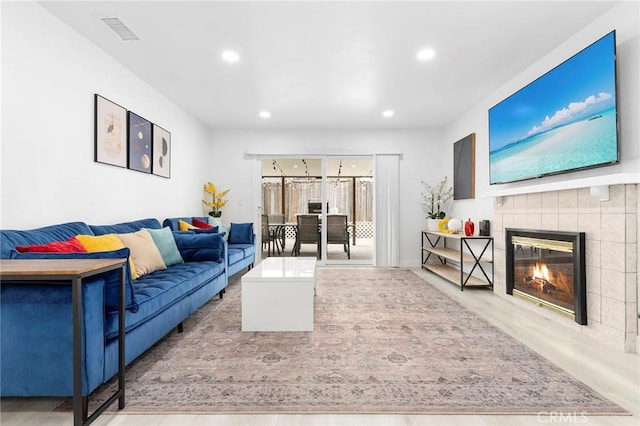 living room featuring visible vents, baseboards, a tile fireplace, light wood-type flooring, and recessed lighting