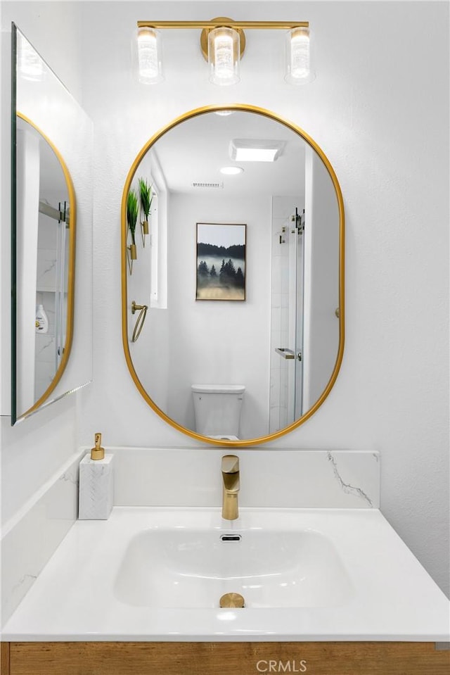 bathroom with visible vents, vanity, and toilet