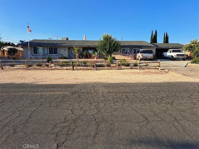 ranch-style house featuring driveway and a fenced front yard