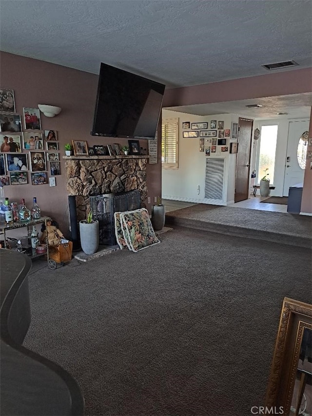 19010 Waseca Rd, Apple Valley, CA 92307 - living room with a stone fireplace, visible vents, carpet floors, and a textured ceiling