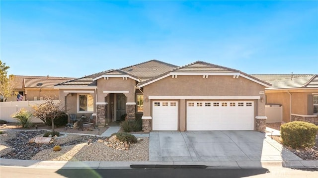 view of front of property featuring an attached garage, stucco siding, concrete driveway, stone siding, and a tile roof