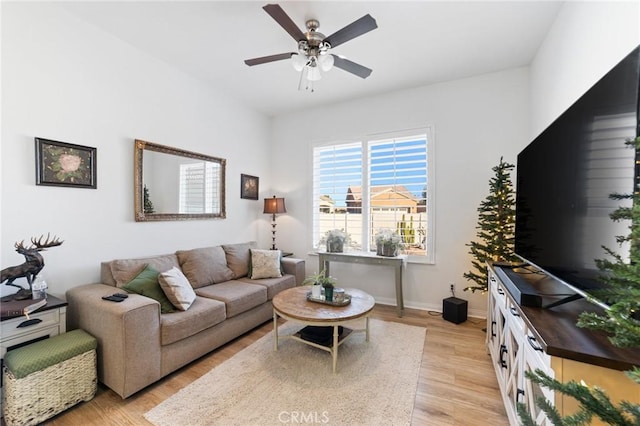 living area featuring baseboards, light wood-type flooring, and ceiling fan