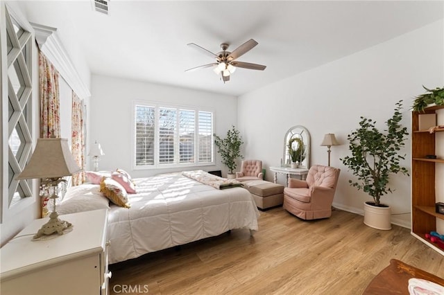 bedroom with a ceiling fan, visible vents, light wood finished floors, and baseboards