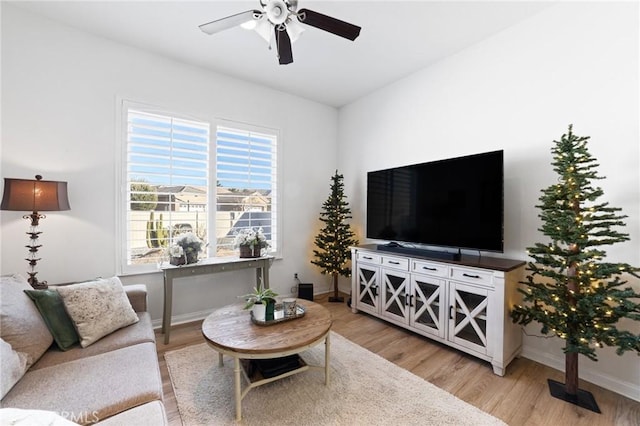 living area with light wood finished floors, baseboards, and ceiling fan