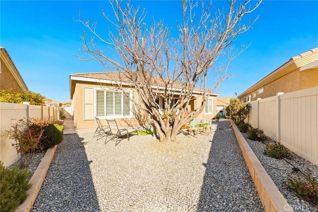 rear view of house featuring a patio area, stucco siding, and a fenced backyard