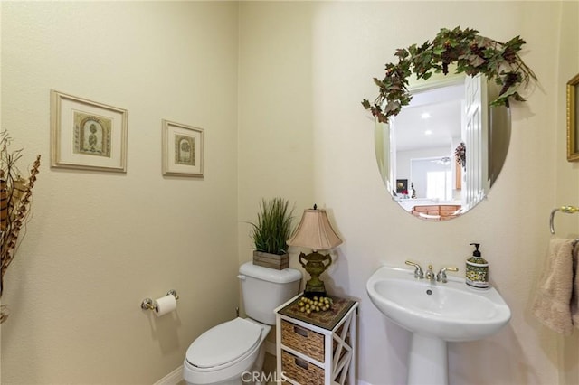 half bath with a sink, baseboards, and toilet