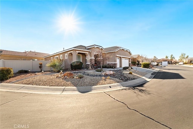 view of front of house featuring fence, driveway, an attached garage, stucco siding, and stone siding