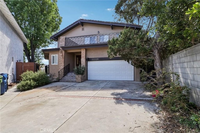 view of front of home featuring a garage, a balcony, driveway, and fence