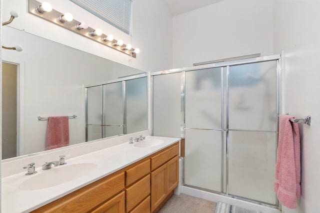 full bathroom featuring a sink, a shower with shower door, and double vanity