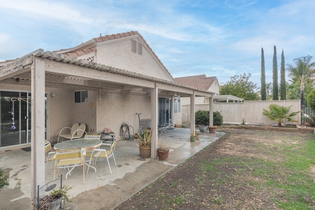 back of property with a patio area, stucco siding, a pergola, and fence