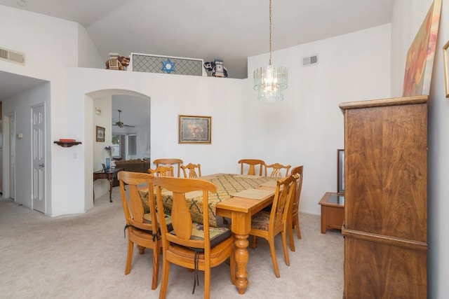 dining room with light colored carpet, lofted ceiling, arched walkways, and visible vents