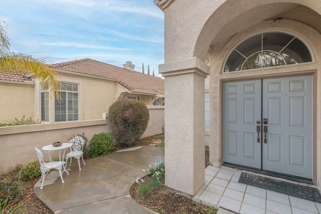 view of exterior entry with a tiled roof and stucco siding