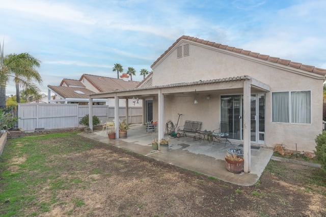 rear view of property with stucco siding, a patio, and fence