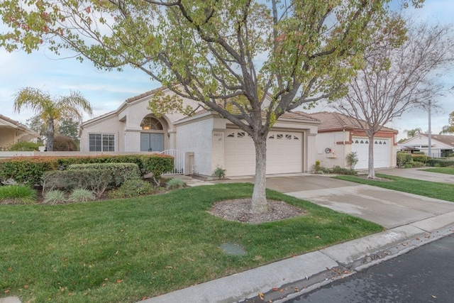 view of front facade featuring stucco siding, a front lawn, driveway, a tile roof, and a garage