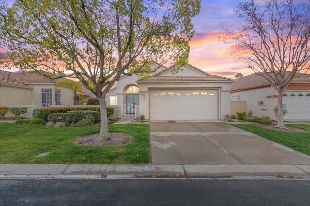 view of front facade with stucco siding, a front lawn, driveway, a garage, and a tiled roof