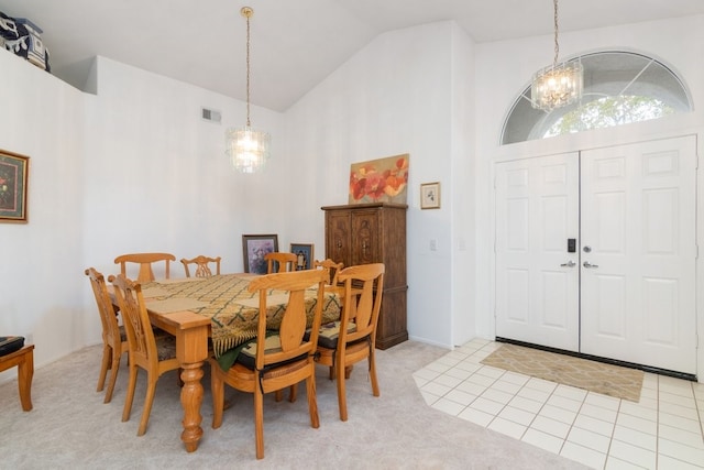 dining room with an inviting chandelier, light carpet, visible vents, and high vaulted ceiling