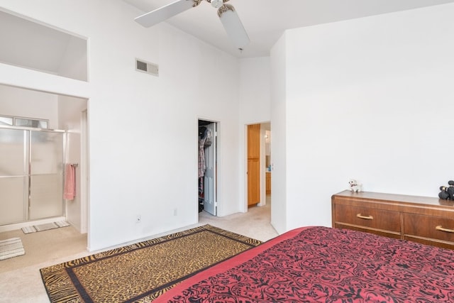 bedroom with light carpet, visible vents, high vaulted ceiling, and a walk in closet