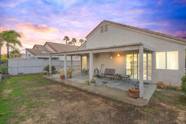 rear view of property with a patio area, fence, and stucco siding