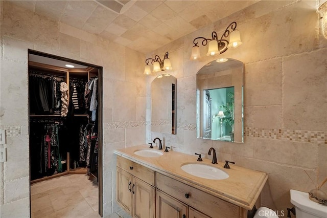 bathroom with double vanity, toilet, tile walls, and a sink