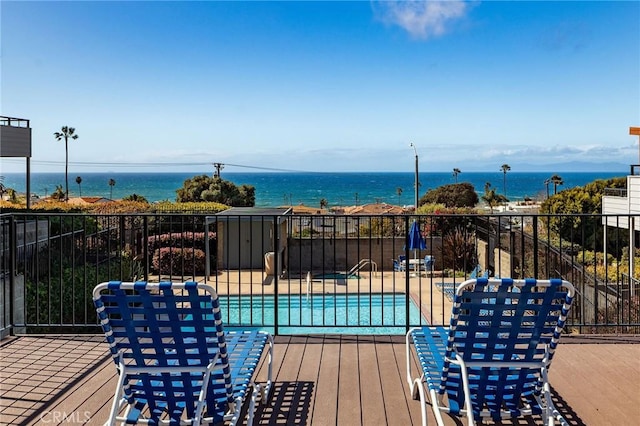 wooden deck with a community pool, fence, and a water view