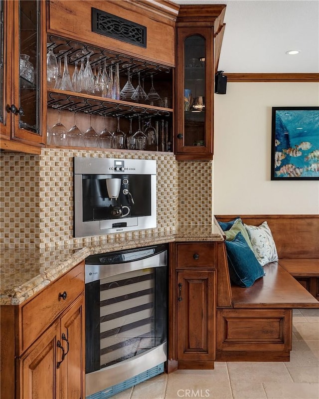 bar with beverage cooler, light tile patterned flooring, ornamental molding, a bar, and tasteful backsplash