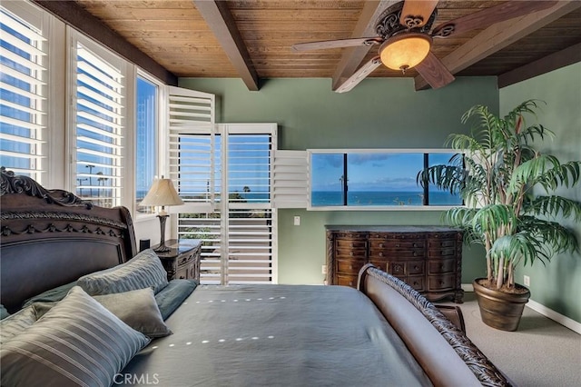 interior space featuring beamed ceiling, carpet floors, baseboards, wood ceiling, and ceiling fan