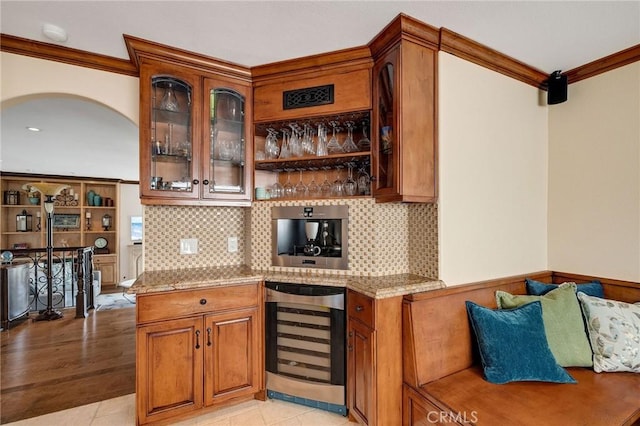 bar featuring tasteful backsplash, beverage cooler, a dry bar, ornamental molding, and light tile patterned flooring