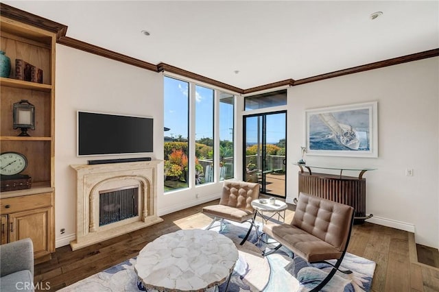 living area with a premium fireplace, crown molding, baseboards, and hardwood / wood-style flooring