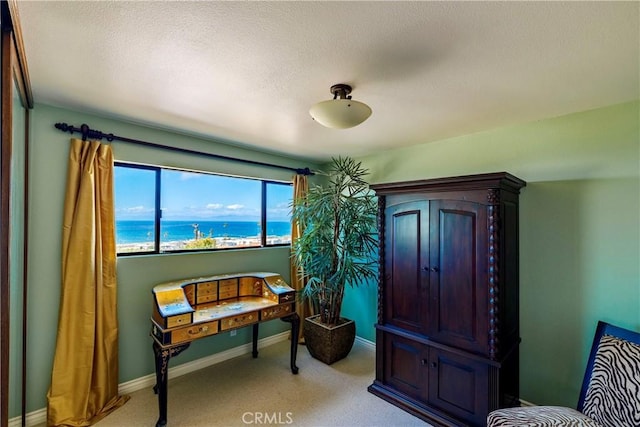 sitting room with light carpet, a textured ceiling, baseboards, and a water view